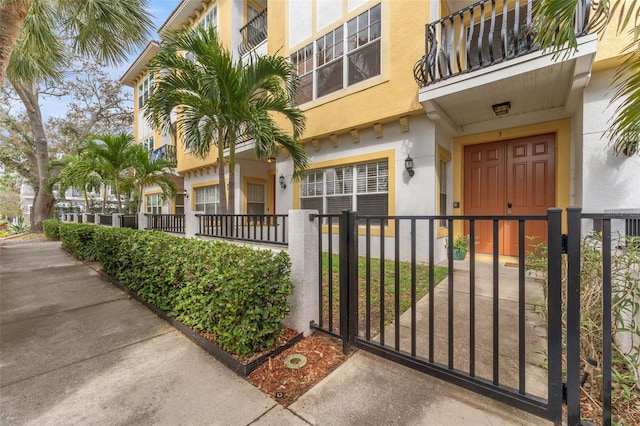 doorway to property with a gate, fence, and stucco siding