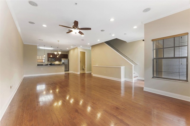 unfurnished living room with baseboards, a ceiling fan, crown molding, and wood finished floors