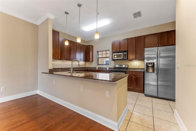 kitchen featuring a sink, visible vents, appliances with stainless steel finishes, dark stone countertops, and pendant lighting