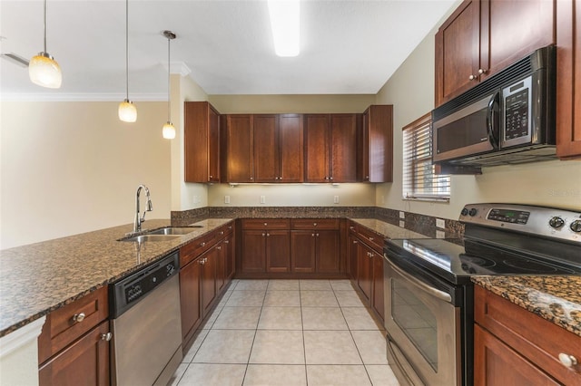 kitchen featuring dark stone counters, stainless steel appliances, a sink, and decorative light fixtures