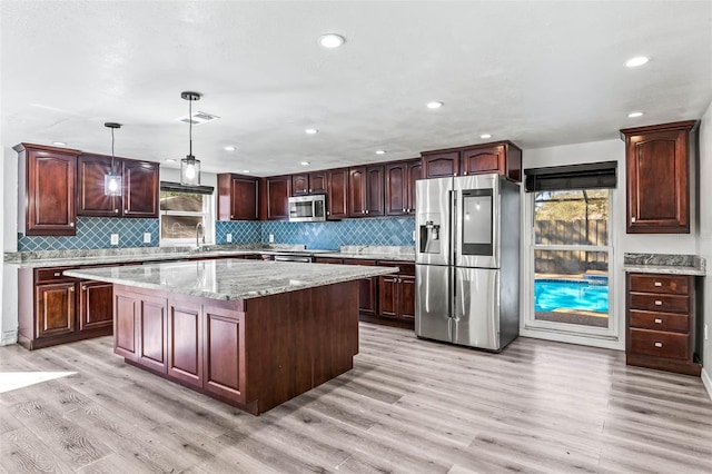 kitchen featuring visible vents, a center island, hanging light fixtures, stainless steel appliances, and light wood-type flooring