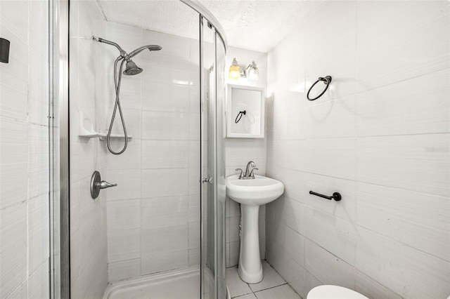 full bathroom with toilet, a shower stall, tile walls, and a textured ceiling