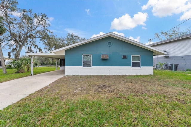 view of side of home featuring an attached carport, concrete driveway, a lawn, and fence