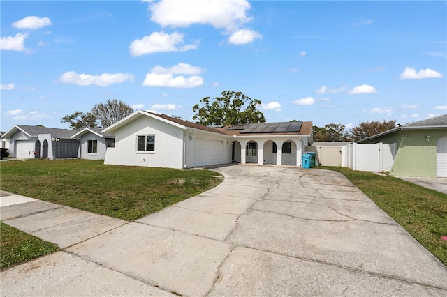 view of front facade with an attached garage, solar panels, concrete driveway, a gate, and a front yard