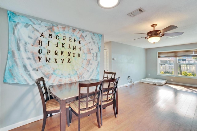 dining room featuring visible vents, ceiling fan, baseboards, and wood finished floors