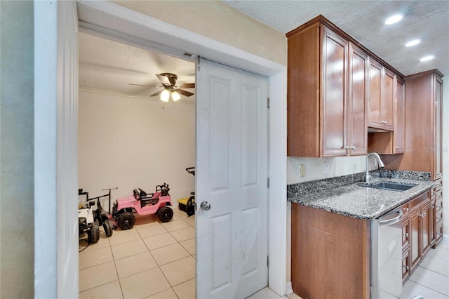 kitchen with brown cabinets, light tile patterned flooring, a sink, and a textured ceiling