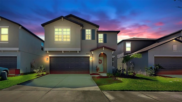 view of front facade with concrete driveway, a lawn, and stucco siding