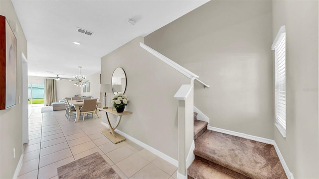 stairway featuring an inviting chandelier, tile patterned flooring, visible vents, and baseboards