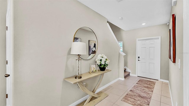 foyer entrance with light tile patterned floors, baseboards, and stairway