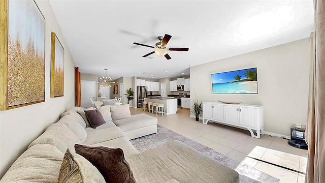 living room with light tile patterned floors, ceiling fan with notable chandelier, and baseboards