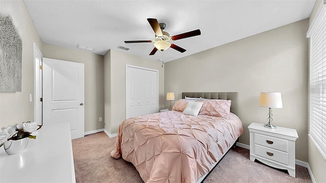 bedroom with baseboards, visible vents, a ceiling fan, light colored carpet, and a closet