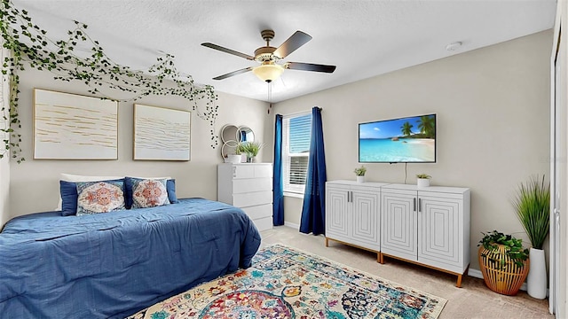 bedroom with a ceiling fan, light carpet, a textured ceiling, and baseboards