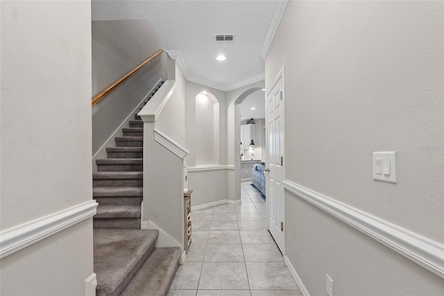 hall featuring light tile patterned floors, arched walkways, visible vents, stairs, and ornamental molding