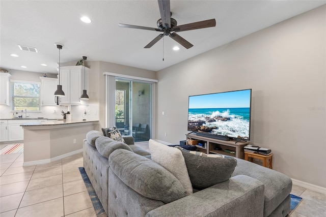 living area with light tile patterned floors, ceiling fan, visible vents, and baseboards