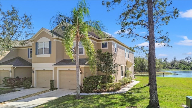 view of property with stucco siding, concrete driveway, a water view, a front yard, and a garage