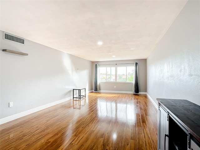 unfurnished living room with light wood-style flooring, visible vents, and baseboards