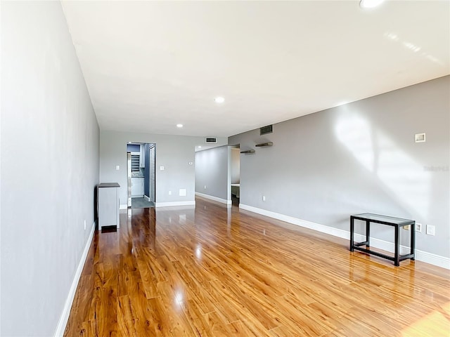 unfurnished living room with visible vents, light wood-style flooring, and baseboards