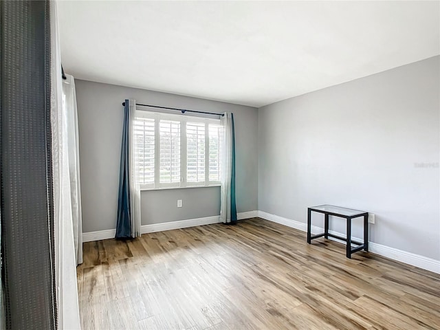 empty room with light wood-type flooring and baseboards