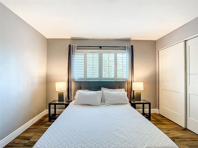 bedroom with dark wood-style floors, a closet, and baseboards