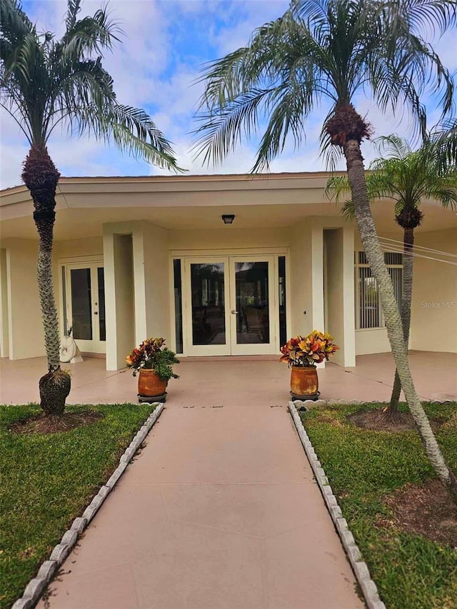 doorway to property featuring french doors and stucco siding