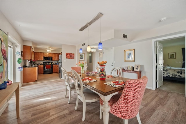 dining room with a ceiling fan, visible vents, and light wood finished floors