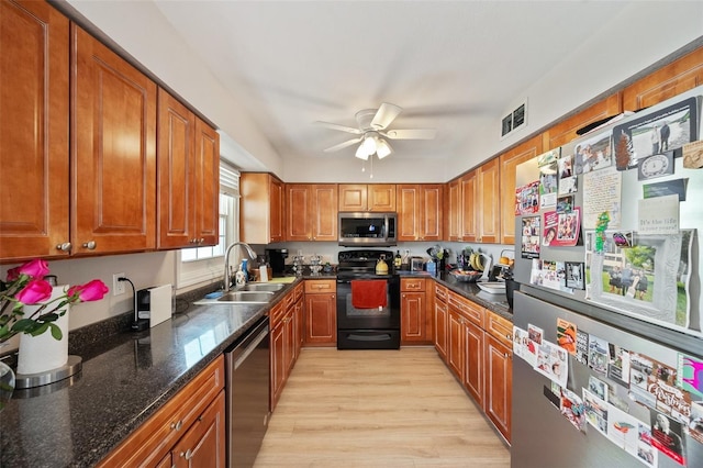 kitchen featuring brown cabinets, visible vents, appliances with stainless steel finishes, light wood-style floors, and a sink