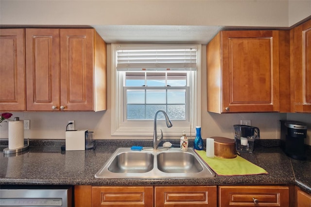 kitchen with brown cabinetry, a sink, and dishwasher