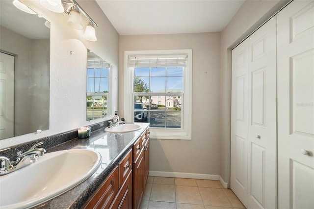 bathroom with double vanity, tile patterned flooring, a sink, and baseboards