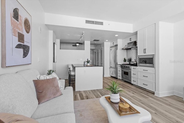 living area with light wood-style floors, visible vents, and baseboards