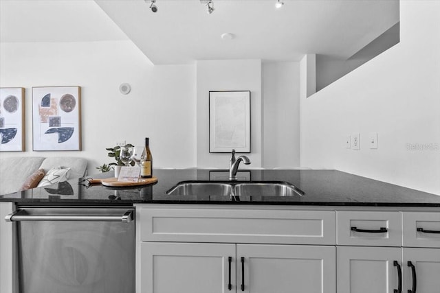 kitchen with dark stone countertops, white cabinetry, a sink, and stainless steel dishwasher