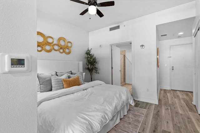 bedroom featuring light wood-style floors, visible vents, ceiling fan, and baseboards