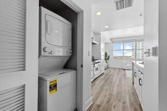 laundry area with light wood-style flooring, recessed lighting, laundry area, stacked washer and dryer, and visible vents