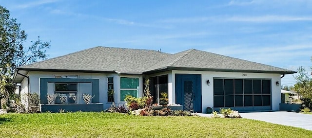 view of front of home with an attached garage, driveway, a front lawn, and a shingled roof