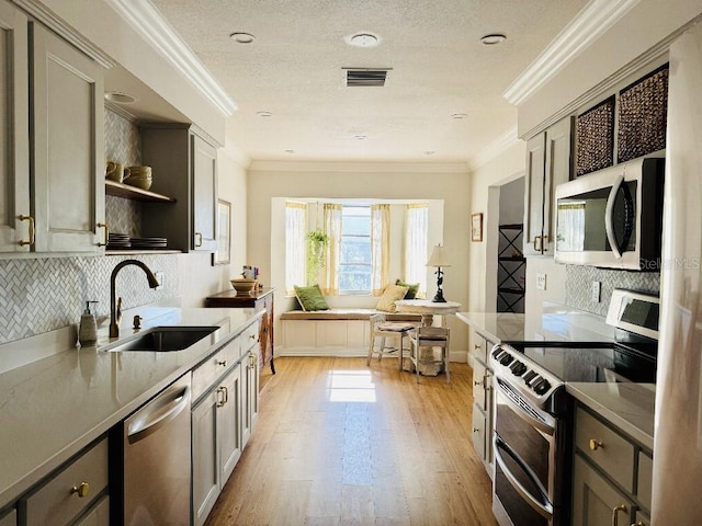 kitchen with stainless steel appliances, gray cabinets, a sink, and open shelves