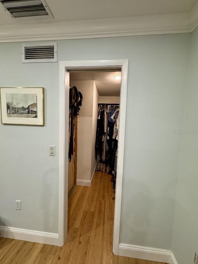 hall with light wood-type flooring, visible vents, and baseboards