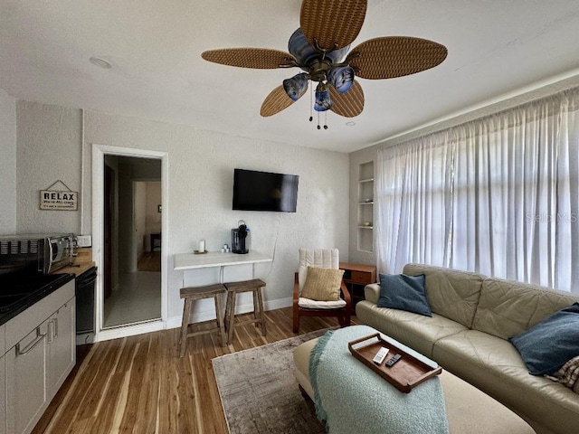 living area with dark wood finished floors, a ceiling fan, and baseboards