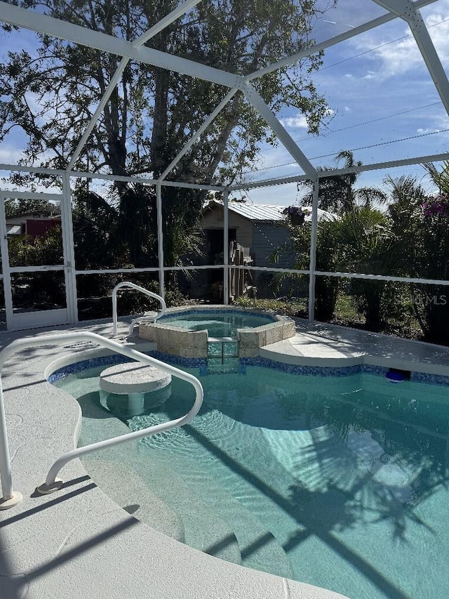 view of pool featuring glass enclosure, a pool with connected hot tub, and a patio area