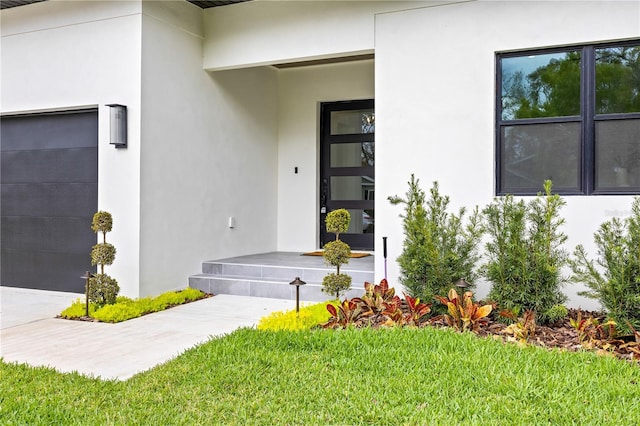 view of exterior entry with a yard and stucco siding