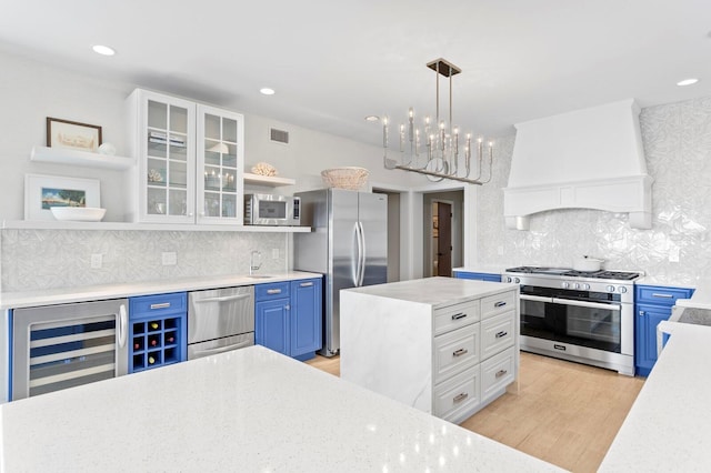 611 Brightwaters Blvd NE, Saint Petersburg, FL 33704 - kitchen with blue cabinetry, custom exhaust hood, open shelves, appliances with stainless steel finishes, and beverage cooler