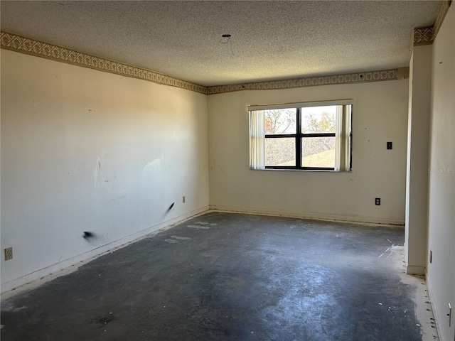 spare room with a textured ceiling and concrete flooring