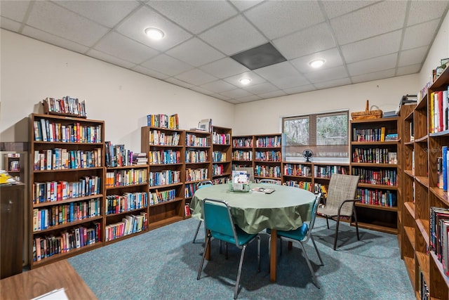 interior space with carpet, a drop ceiling, wall of books, and recessed lighting