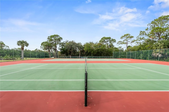 view of tennis court with community basketball court and fence