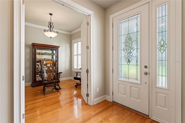 entrance foyer featuring baseboards, ornamental molding, and light wood-style floors