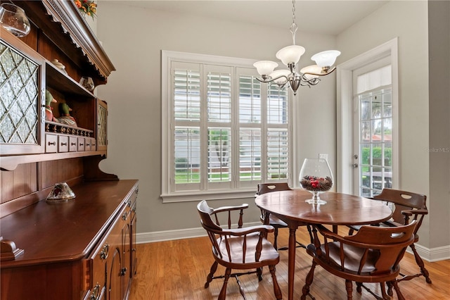 dining room featuring a chandelier, light wood-style flooring, and baseboards