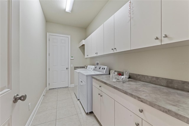 laundry area with light tile patterned floors, cabinet space, baseboards, and separate washer and dryer