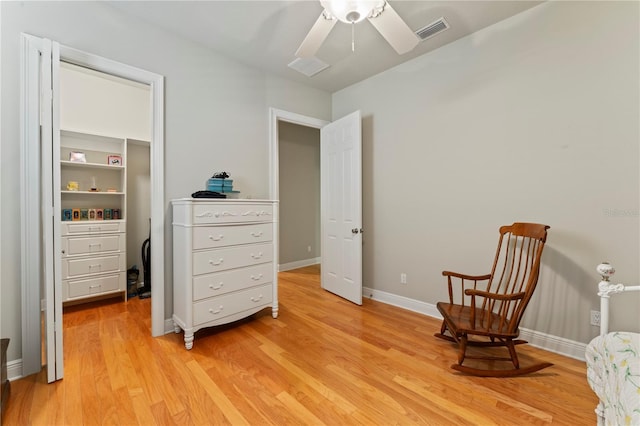 living area featuring baseboards, ceiling fan, visible vents, and light wood-style floors