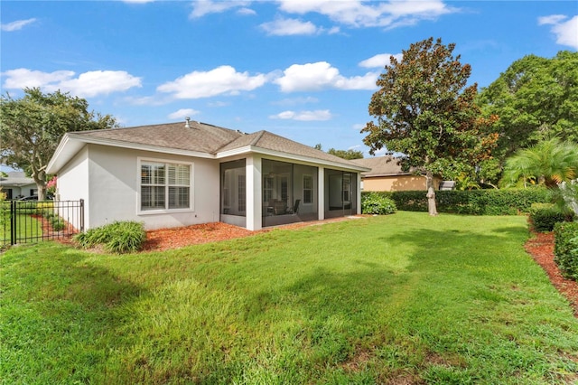 back of property featuring a sunroom, fence, a lawn, and stucco siding