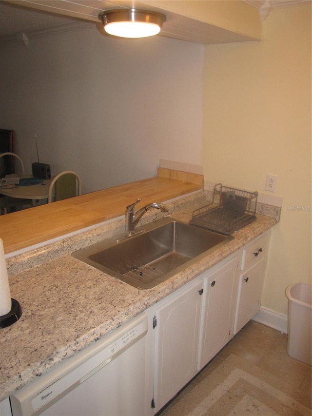 kitchen featuring dishwasher, light countertops, a sink, and white cabinetry