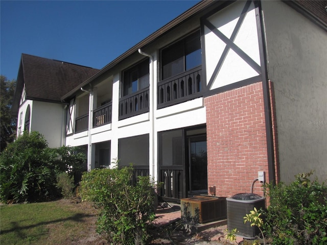 rear view of property with central AC unit, brick siding, and stucco siding