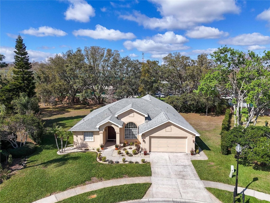 view of front of house featuring concrete driveway, a front lawn, an attached garage, and stucco siding